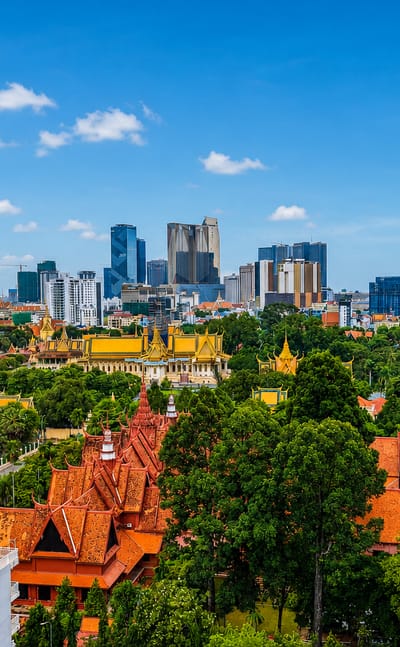 Phnom Penh's golden-spired Royal Palace amid lush gardens with the modern riverfront skyline behind