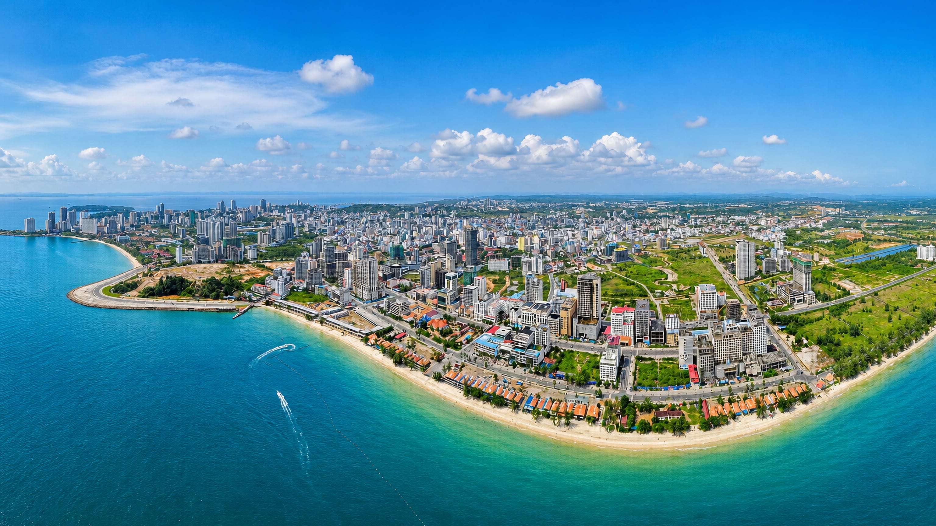 Aerial view of Sihanoukville, Cambodia, its high-rise skyline curving along a sandy beach and turquoise bay.