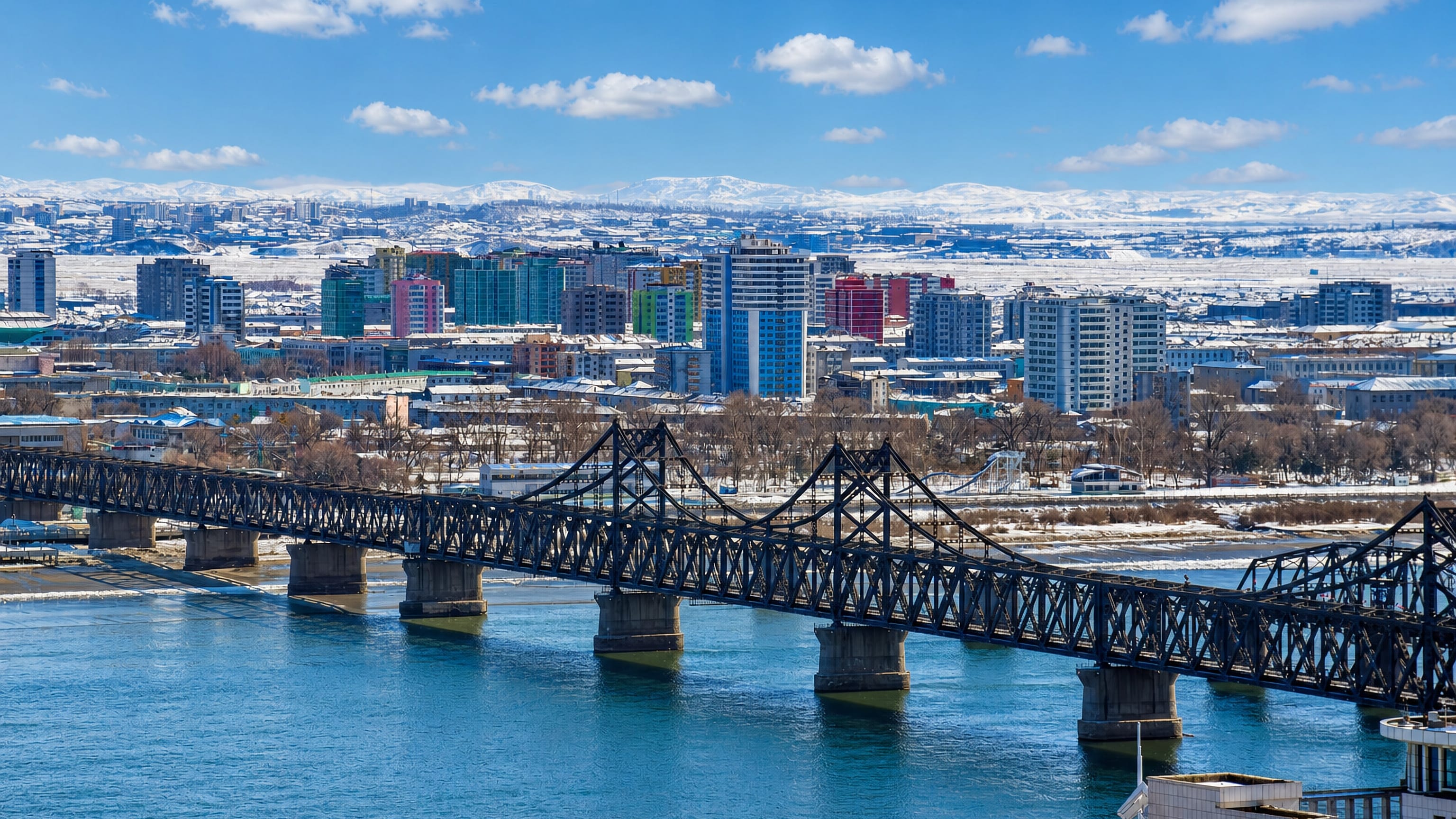 The Sino-Korean Friendship Bridge over the Yalu River with Sinuiju's colourful riverfront blocks behind