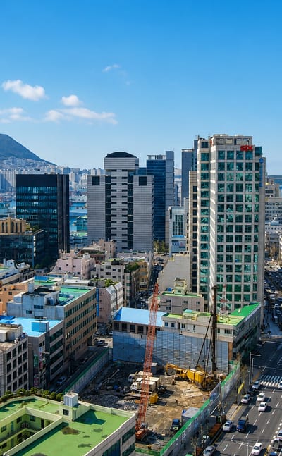 Busan skyline with Busan Tower, harbor and green mountains under a clear blue sky