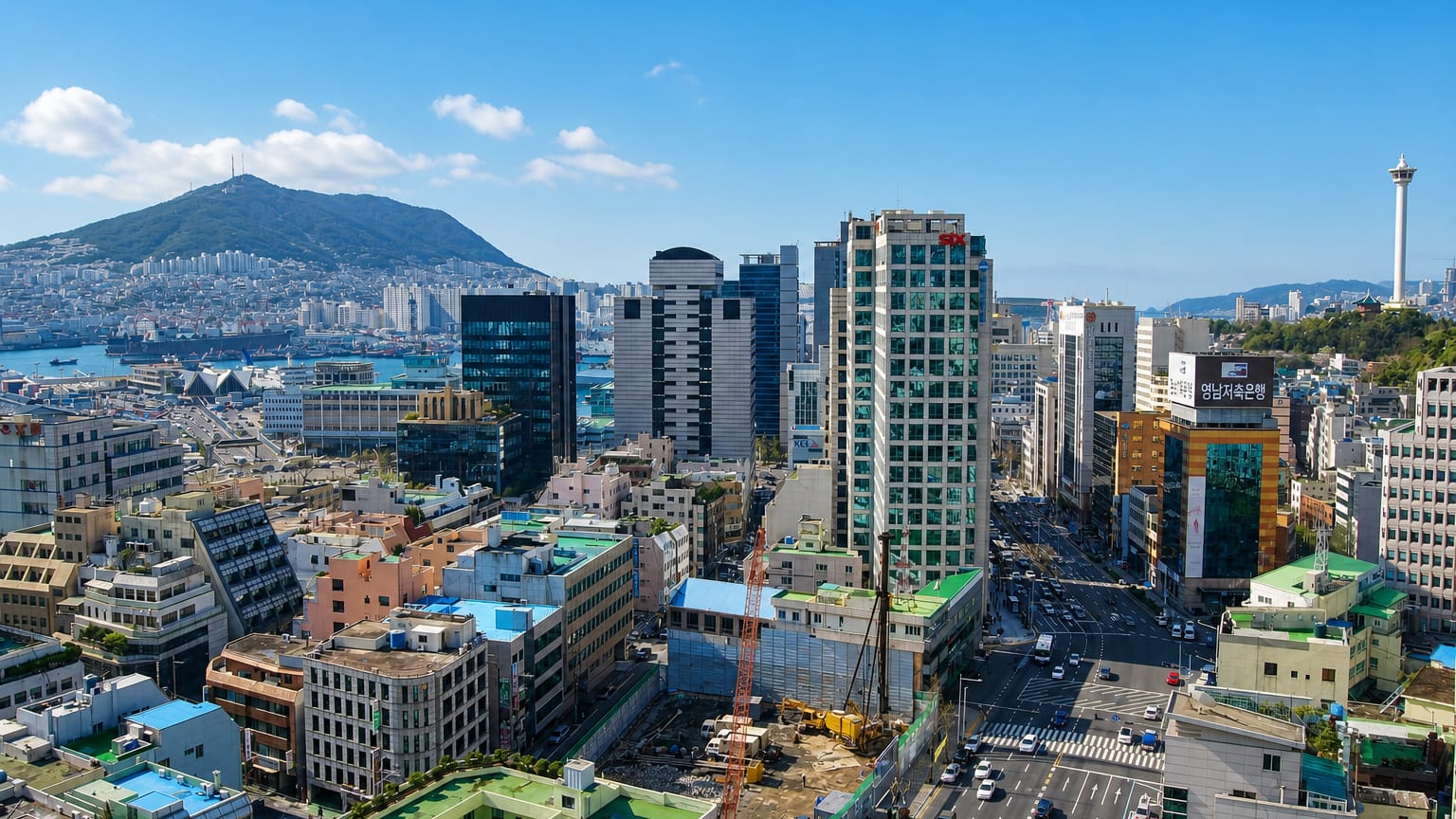 Busan skyline with Busan Tower, harbor and green mountains under a clear blue sky