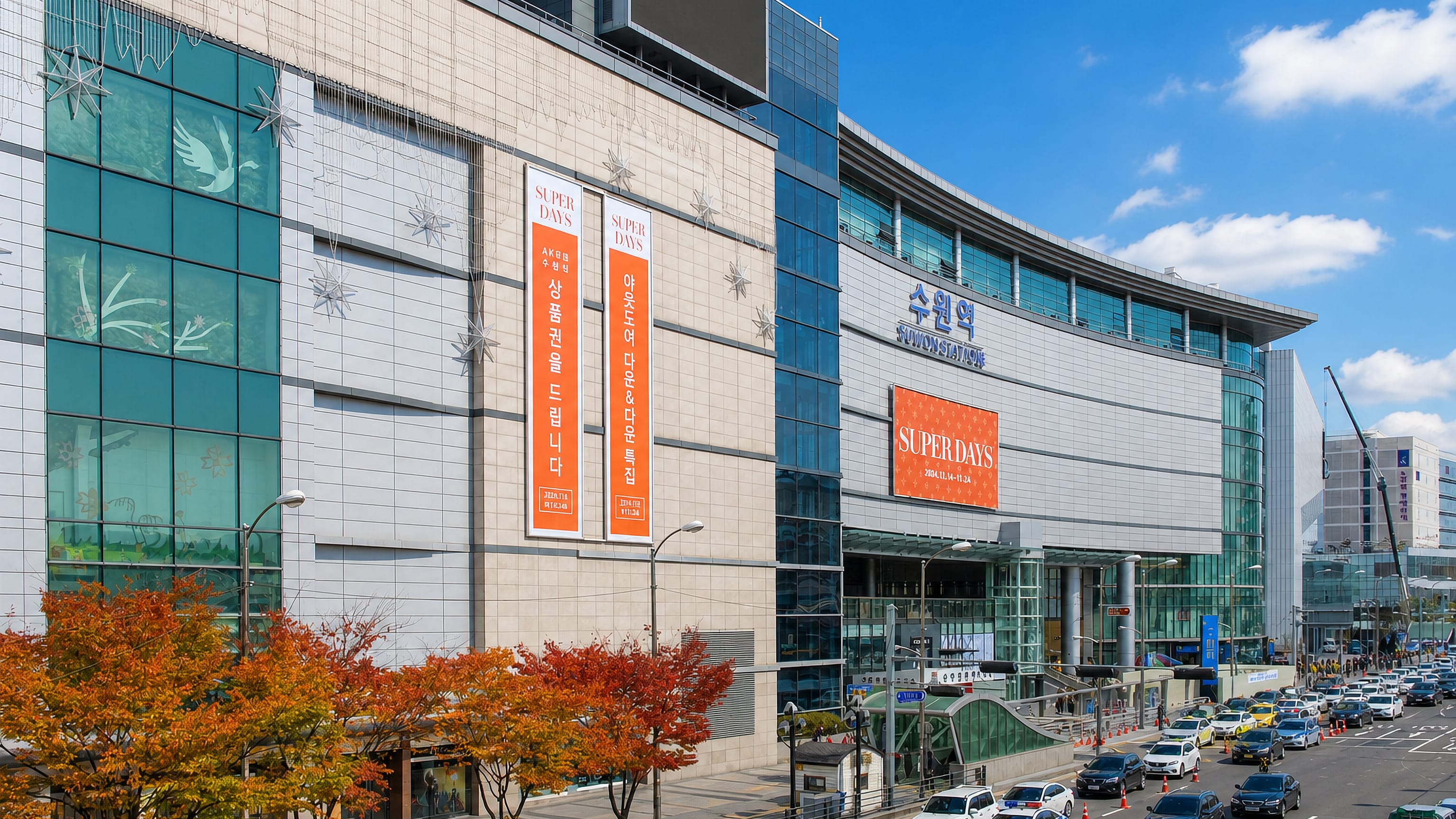 Suwon Station's curved glass and stone frontage above busy traffic on a clear autumn day in Suwon, South Korea