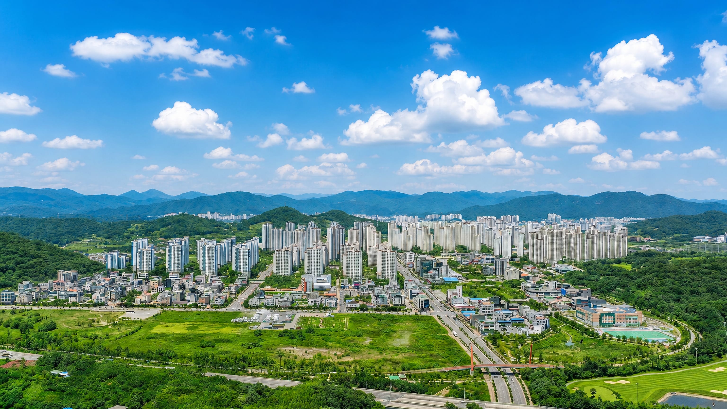 Aerial view of Suncheon's high-rise apartment districts, green fields and surrounding mountain ridges