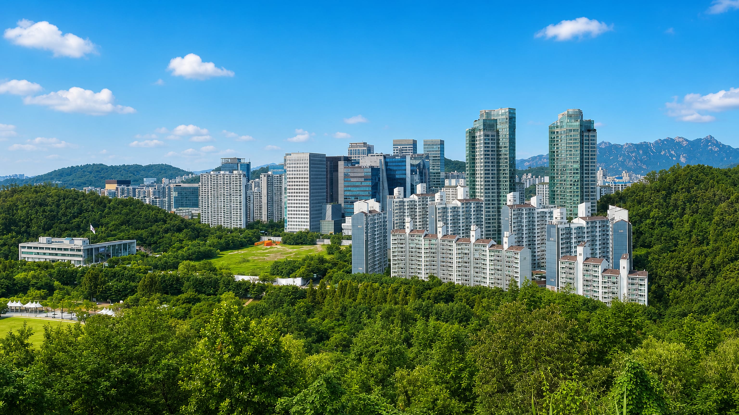 High-rises of Seoul's Mapo District rising beyond a wooded park hill, with granite peaks on the horizon.