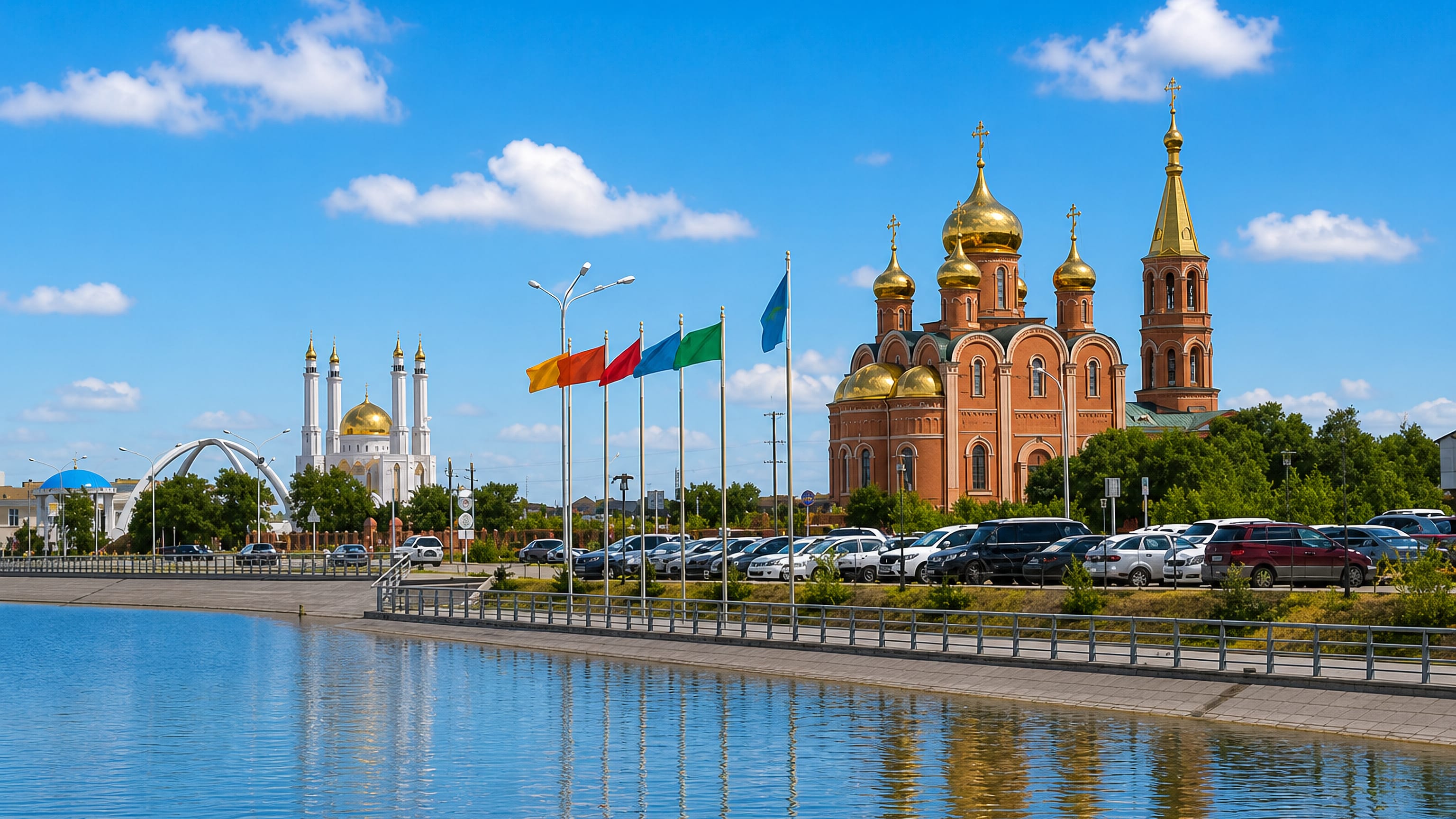Aktobe's red-brick St Nicholas Cathedral and the white Nur Gasyr mosque seen across the riverside embankment.