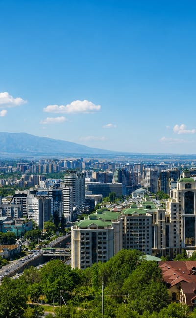Almaty cityscape with green-roofed towers and buildings set against the Tian Shan mountains, Kazakhstan.