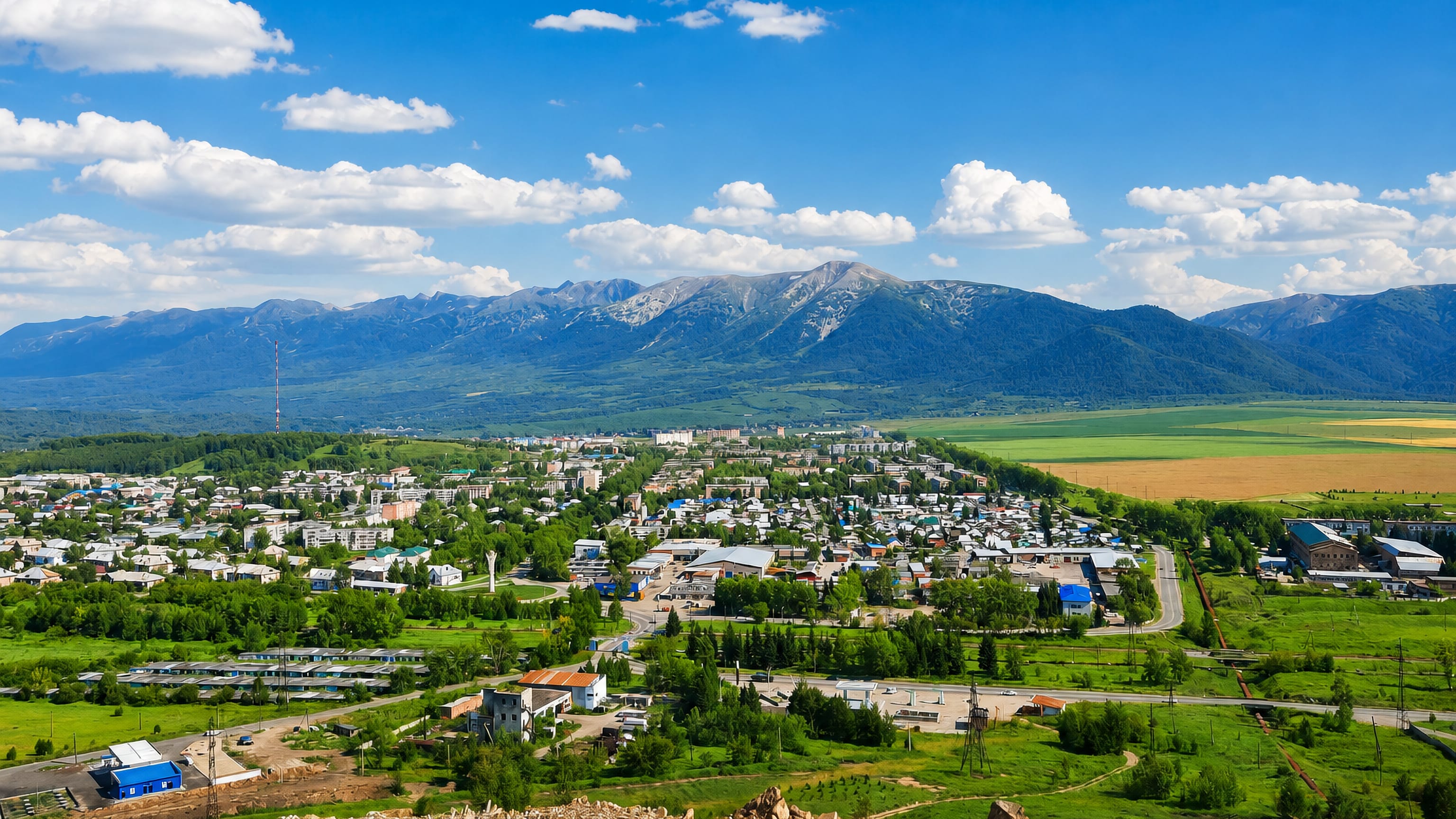 Low-rise Ridder spread across a green valley in East Kazakhstan beneath the forested ridges of the Altai mountains.