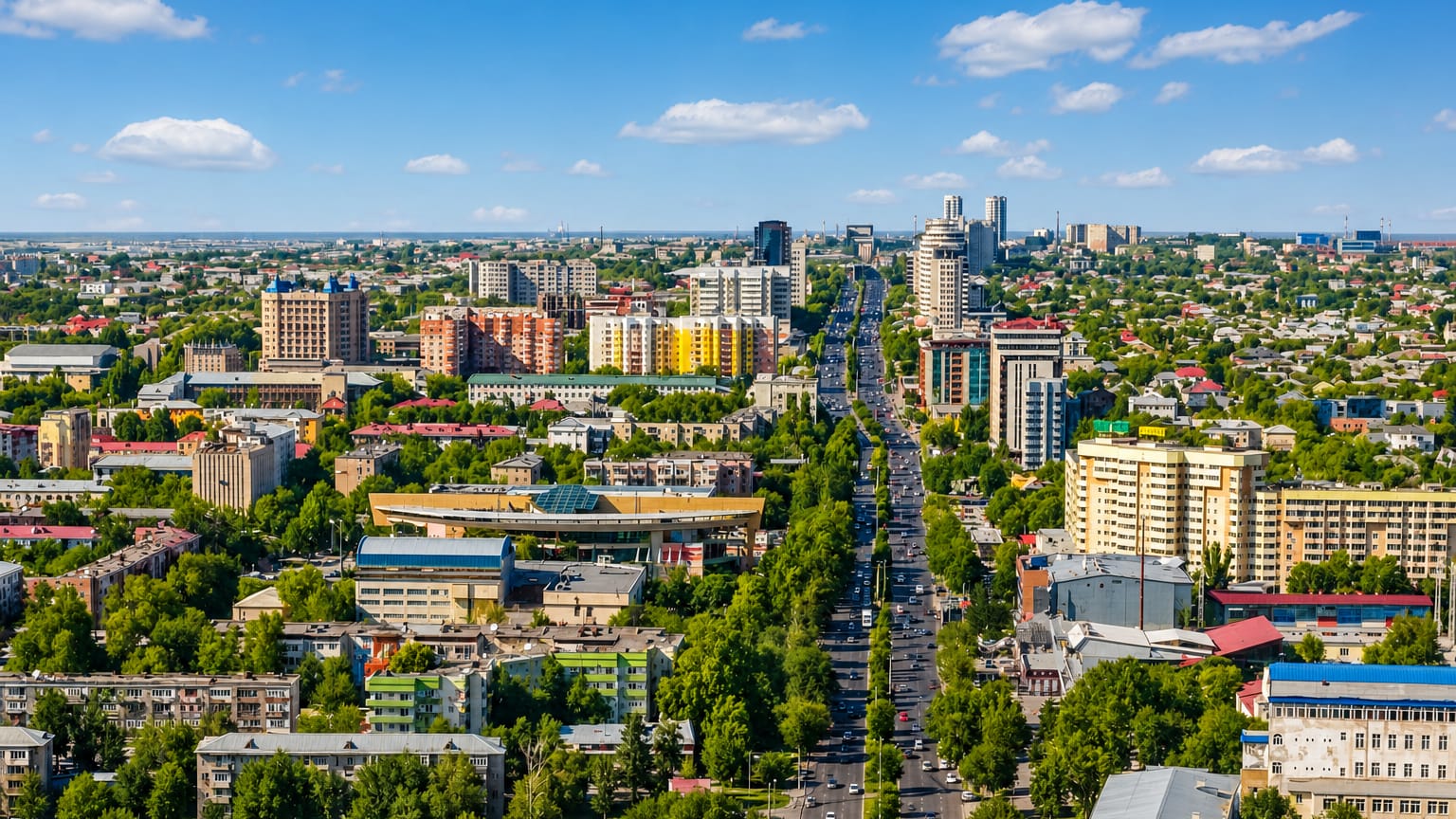 Tree-lined boulevard and mid-rise buildings of Shymkent stretching toward the horizon.
