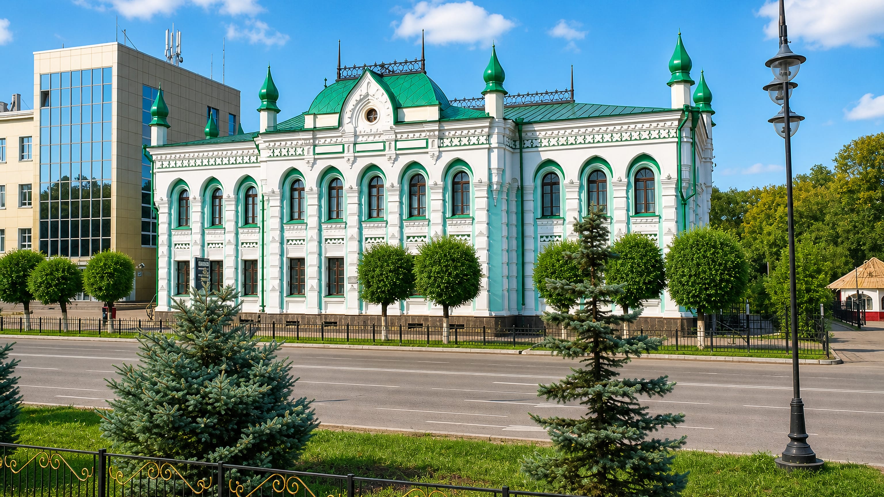 Ornate green-and-white historic merchant building on a tree-lined boulevard in Oral, Kazakhstan