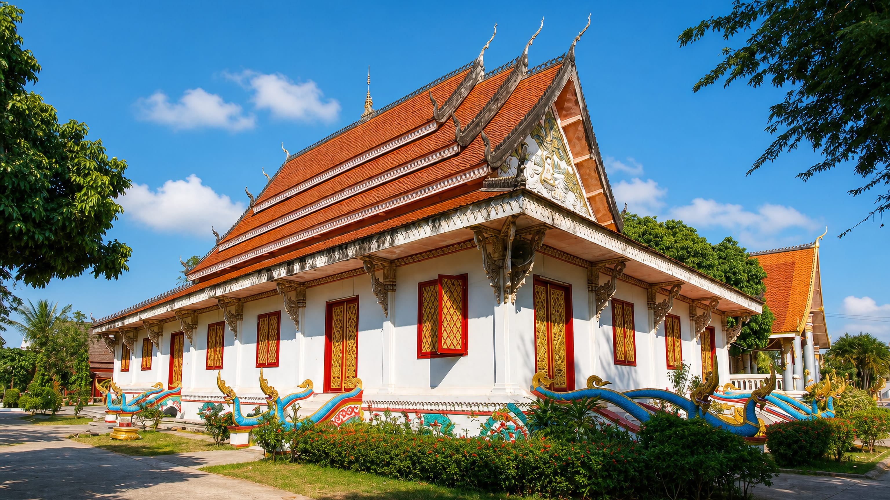 White-and-gold Lao Buddhist temple with a tiered red roof and naga balustrades in Savannakhet, Laos.