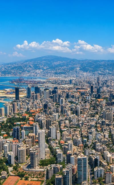 Aerial view of Beirut's dense peninsula reaching into the Mediterranean with its port and Mount Lebanon behind