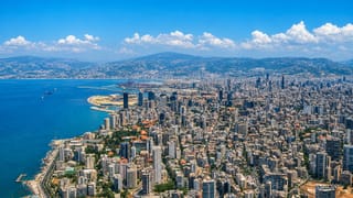 Aerial view of Beirut's dense peninsula reaching into the Mediterranean with its port and Mount Lebanon behind