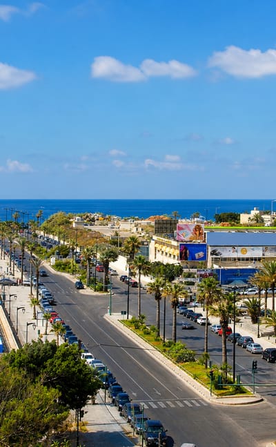 Palm-lined Corniche boulevard along the Mediterranean with the Manara lighthouse in Ras Beirut, Lebanon.