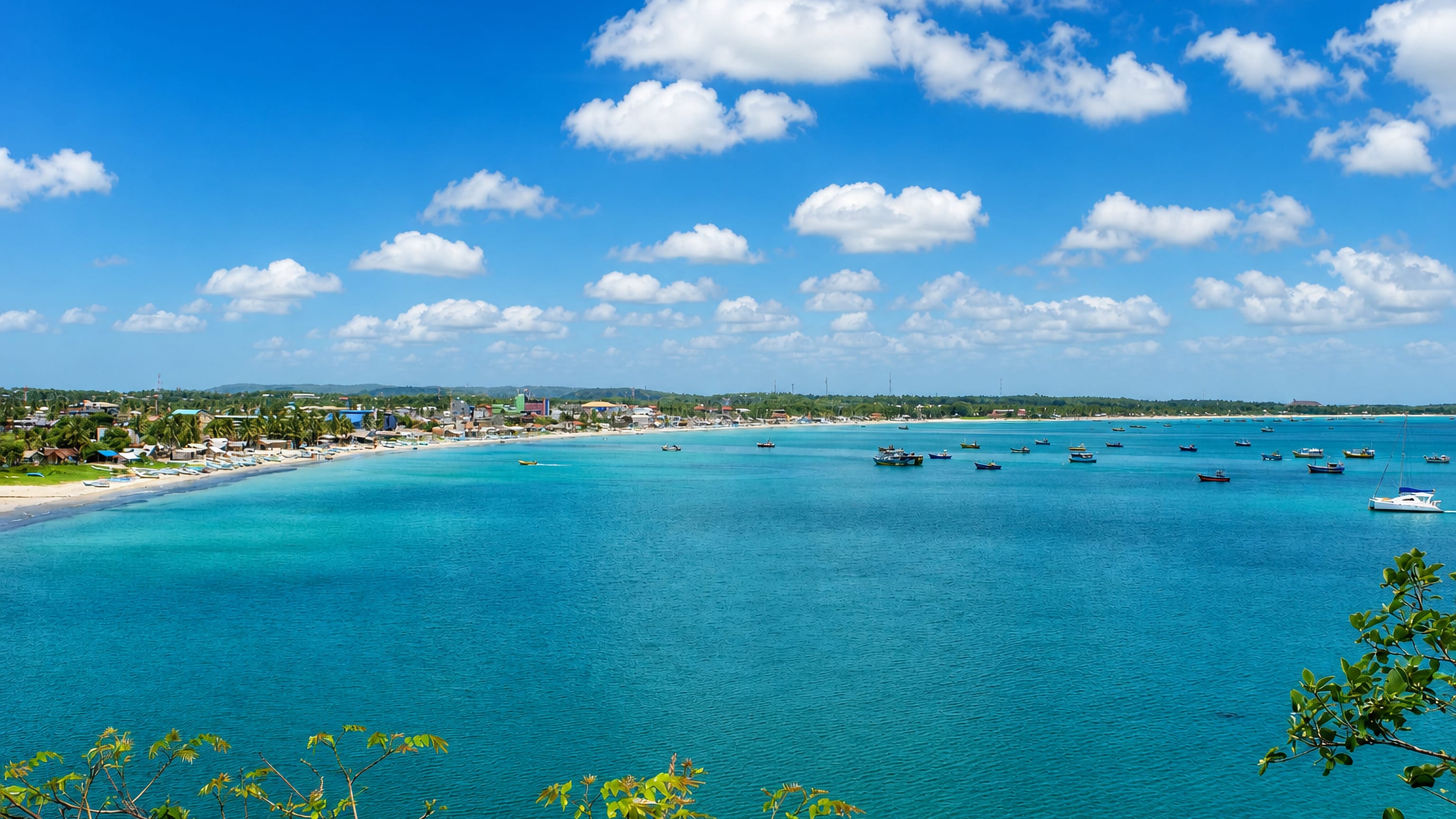 Turquoise natural harbour with fishing boats fronting the low coastal town of Trincomalee, Sri Lanka.