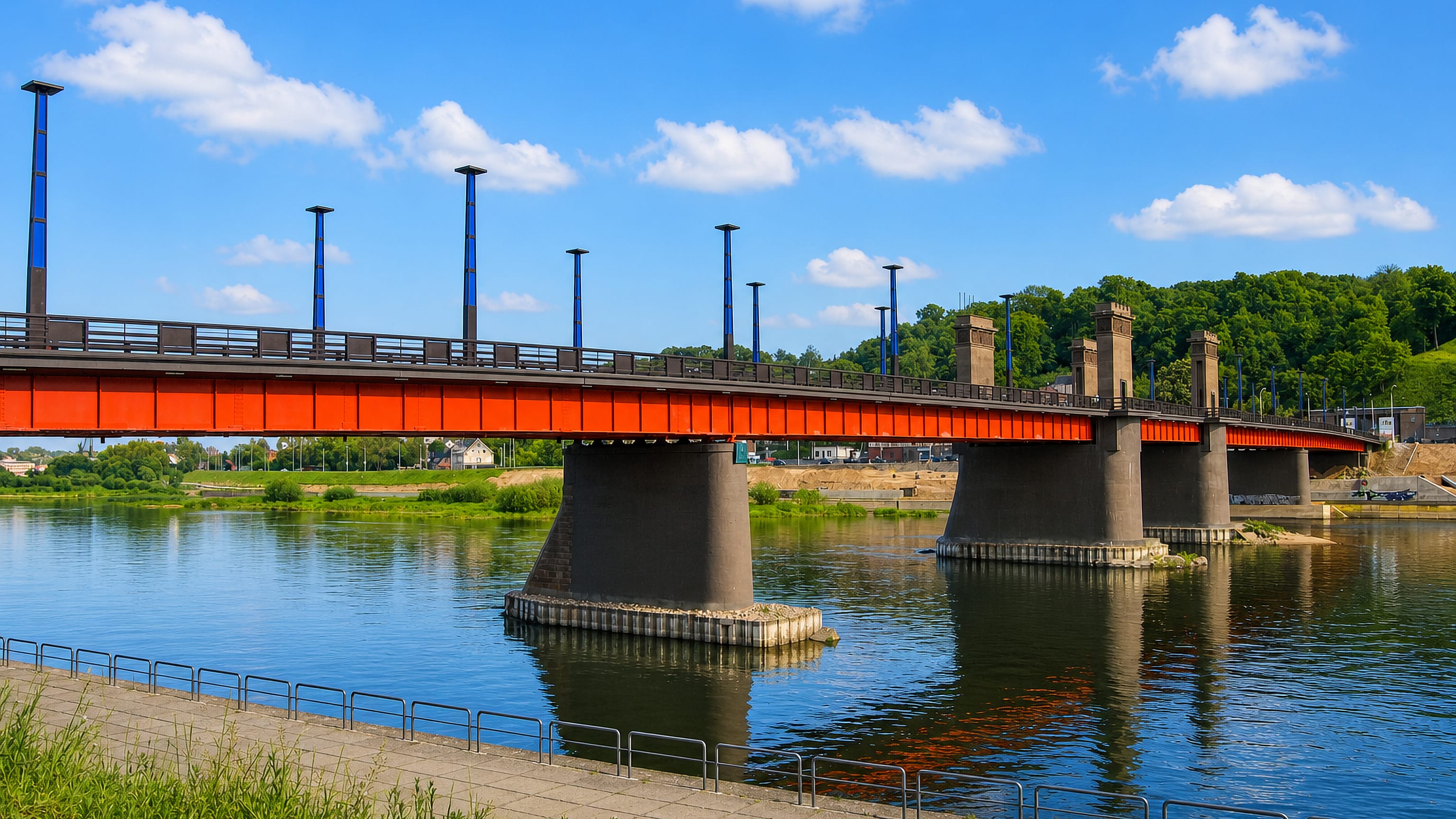 The red steel Aleksotas bridge crossing the Nemunas towards the wooded Aleksotas hill in Kaunas