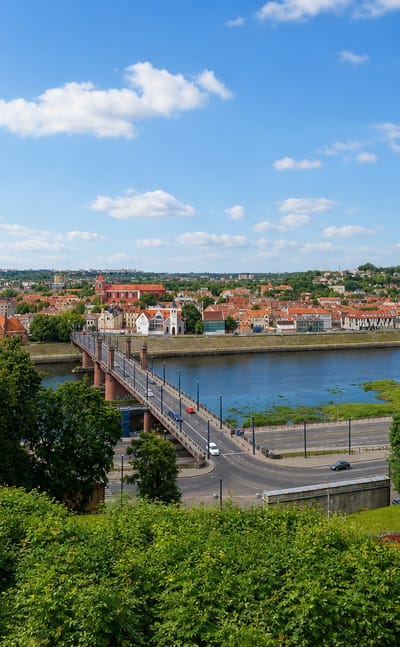 Kaunas Old Town across the river with church spires and a bridge, framed by green parkland