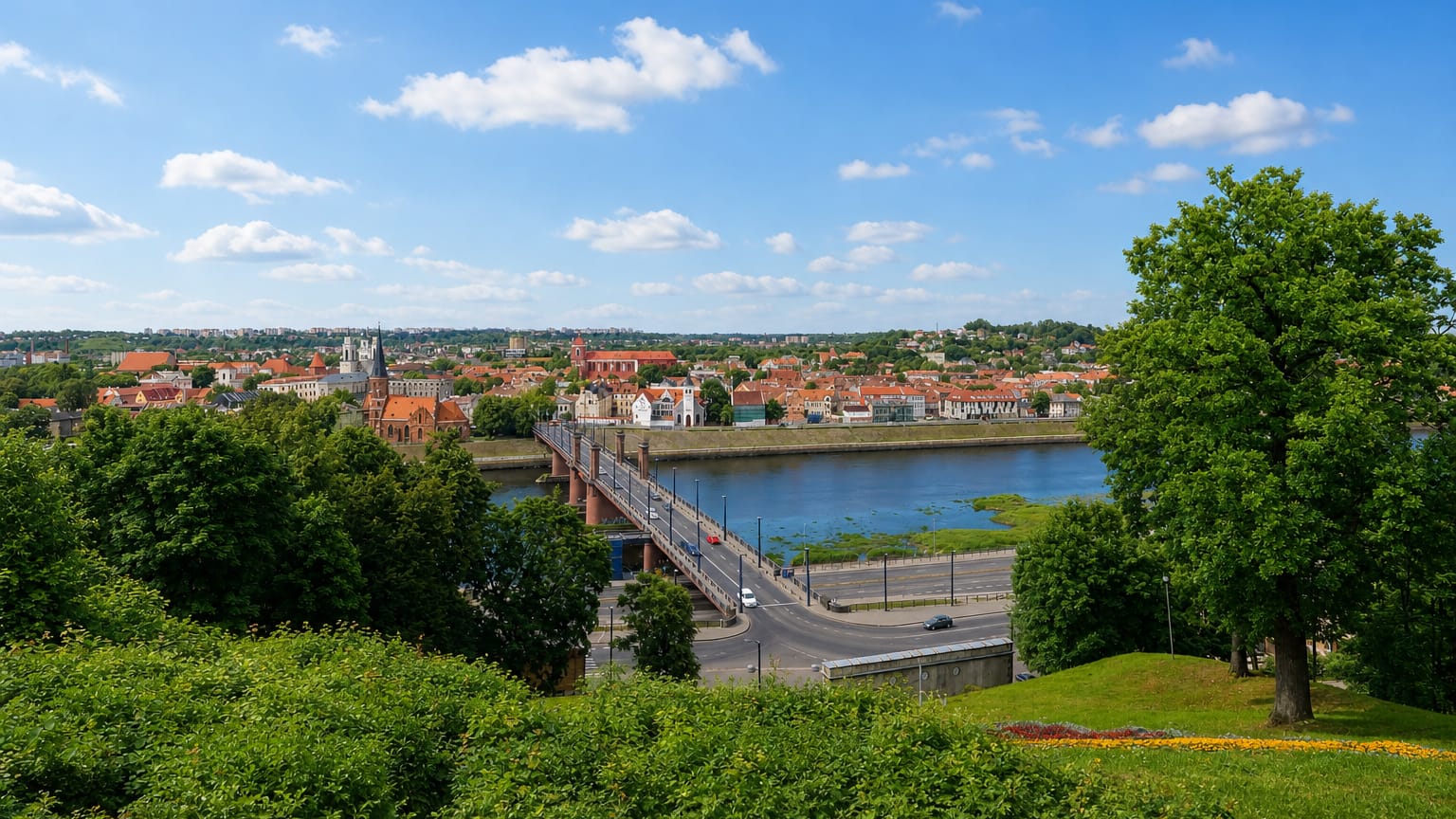 Kaunas Old Town across the river with church spires and a bridge, framed by green parkland