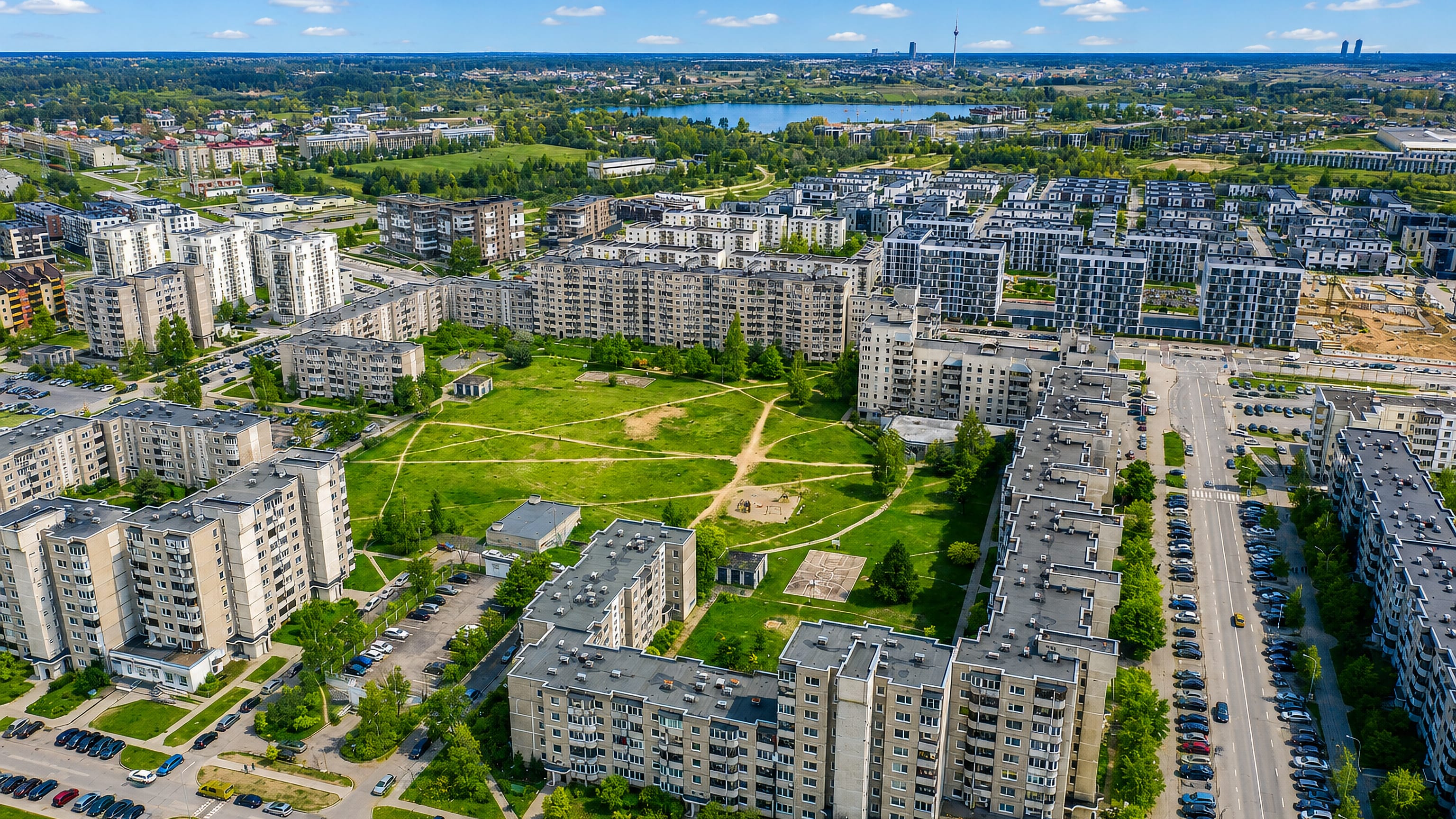 Aerial view over Pilaite's apartment blocks and green courtyards in Vilnius, with the TV tower on the horizon