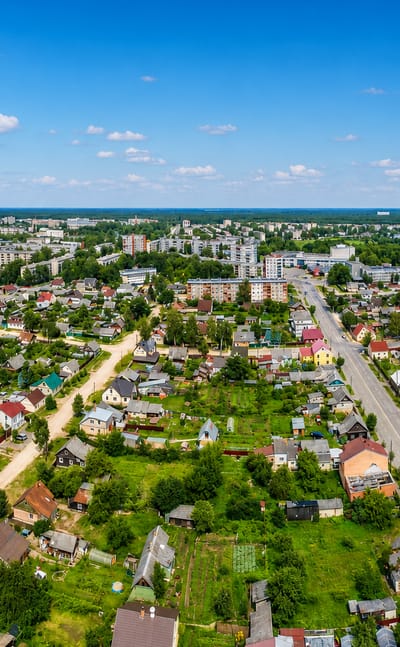 Aerial view over the low-rise houses and apartment blocks of Daugavpils, Latvia, under a blue summer sky.