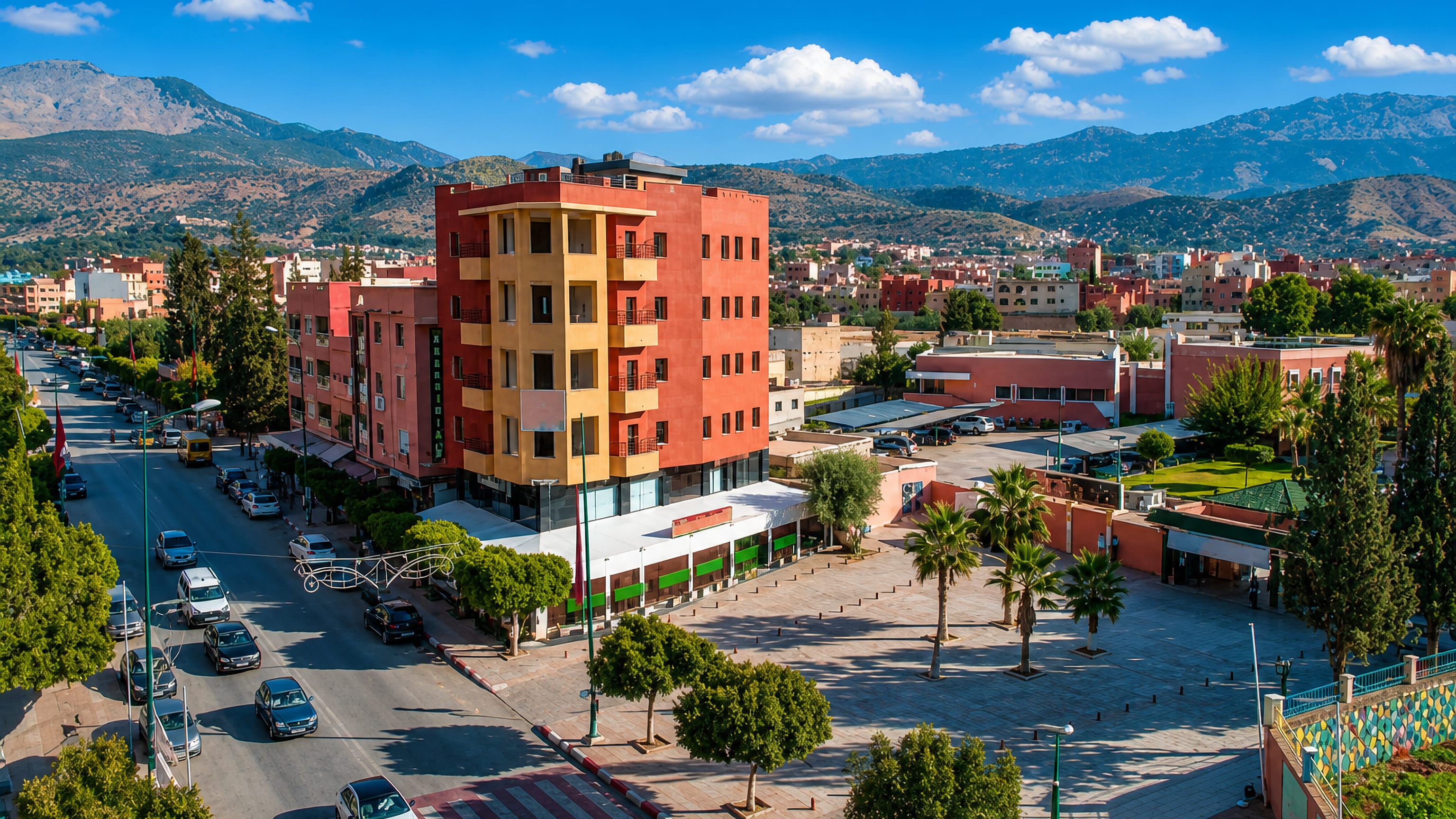 Beni Mellal's palm-lined main boulevard and plaza fronting red-ochre blocks below the Middle Atlas foothills