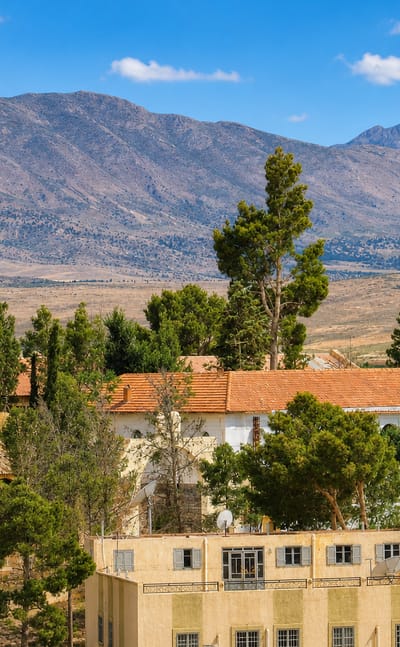 Red-tiled houses among pines below the arid High Atlas ridges at Midelt, Morocco