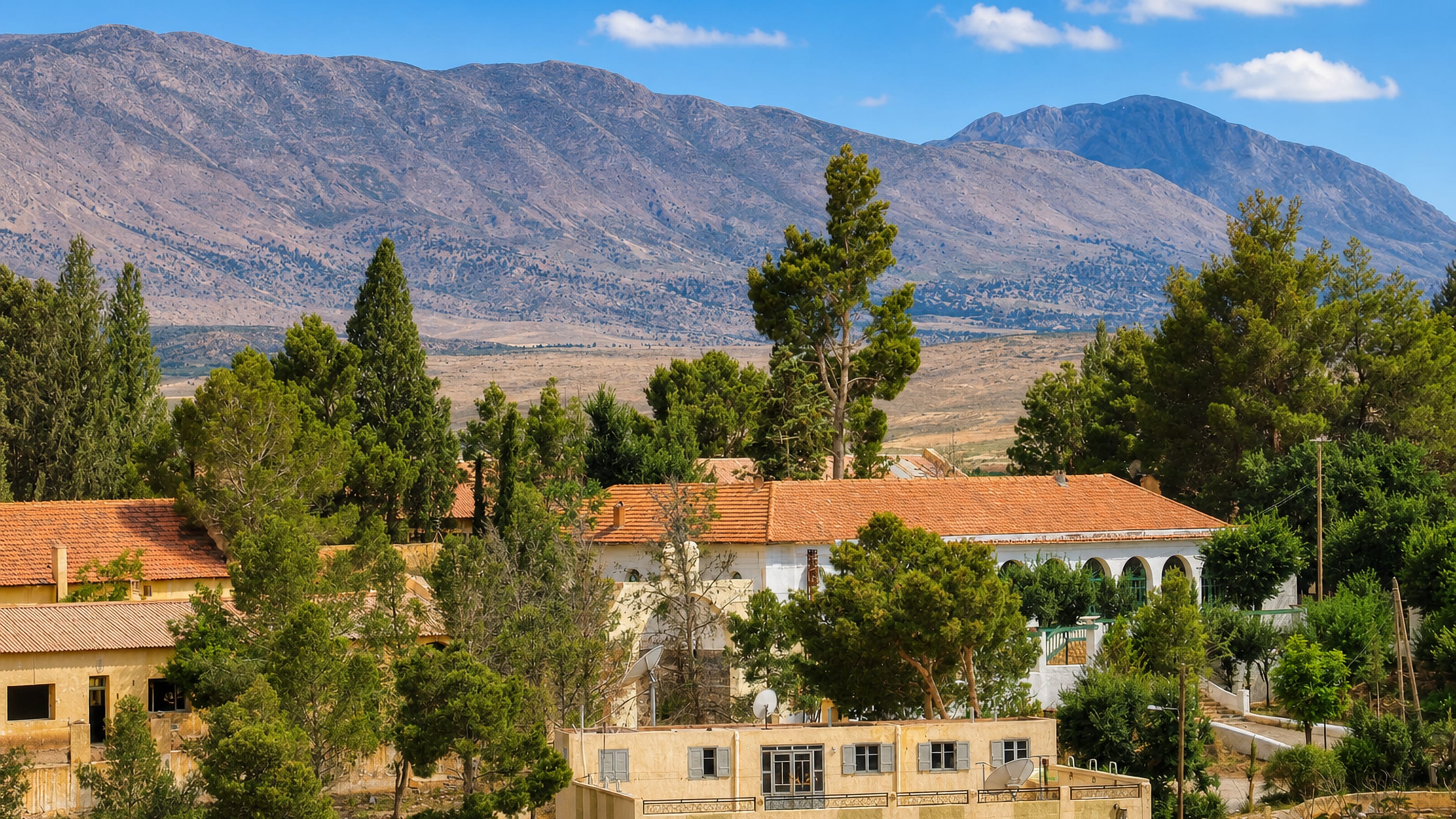 Red-tiled houses among pines below the arid High Atlas ridges at Midelt, Morocco