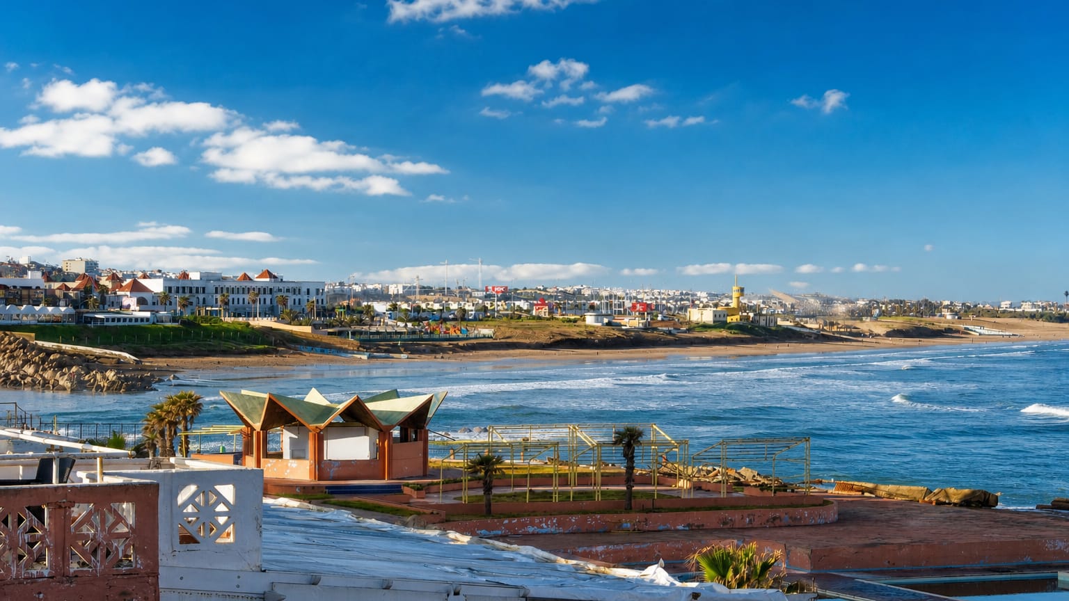 Ain Diab, Casablanca: the Atlantic corniche with a beachfront promenade, waves and the low white city skyline beyond