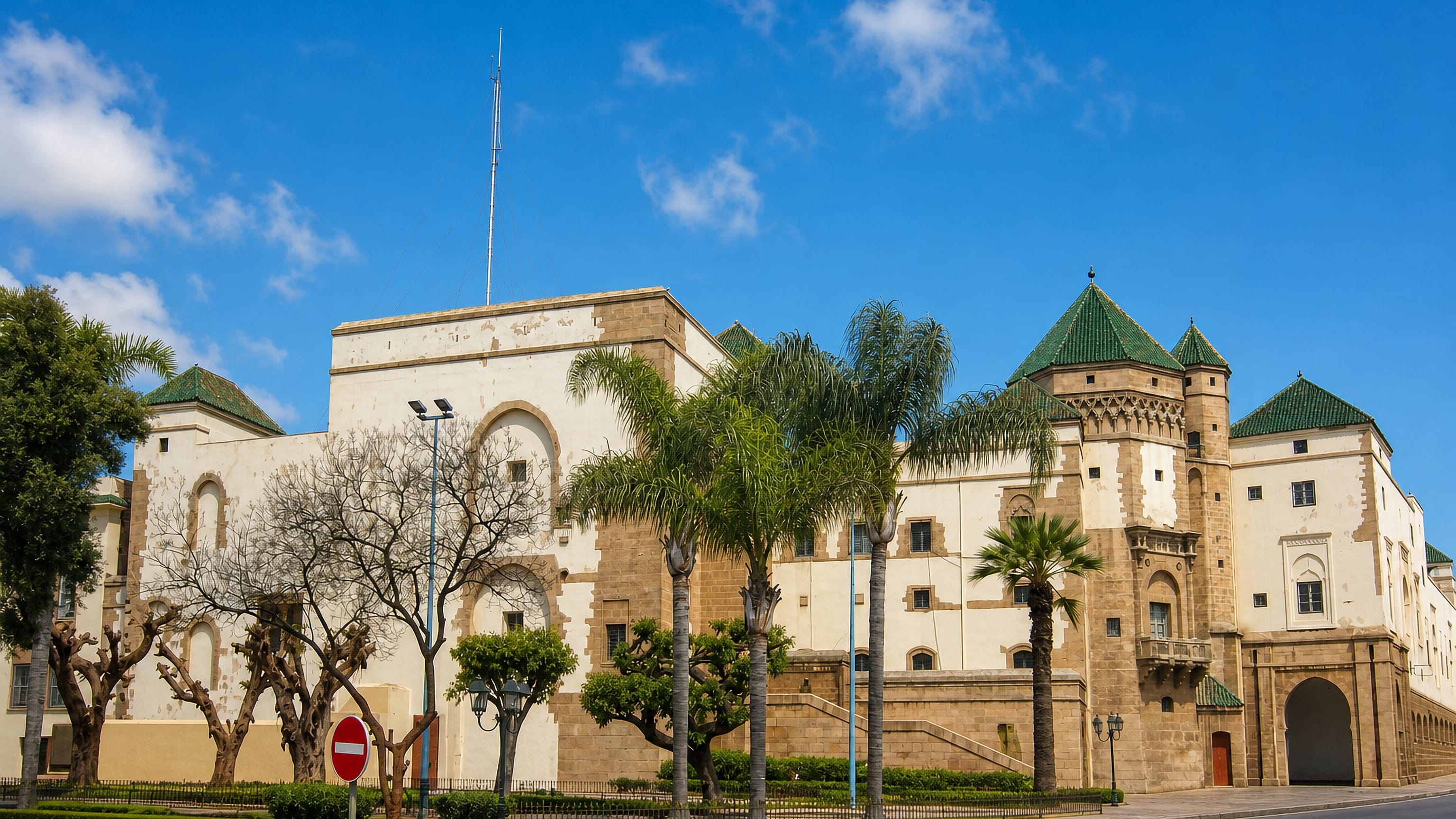 Whitewashed Moorish civic building with green-tiled roofs and palms in the Habous quarter, Casablanca