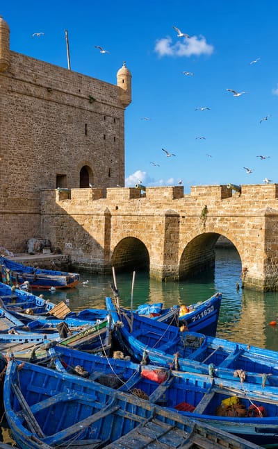 Essaouira's Skala harbour ramparts and stone watchtower above rows of blue wooden fishing boats
