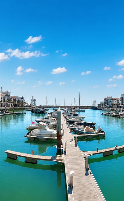 Agadir Marina with moored yachts, wooden pontoons and white waterfront apartment blocks under a blue sky