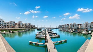 Agadir Marina with moored yachts, wooden pontoons and white waterfront apartment blocks under a blue sky
