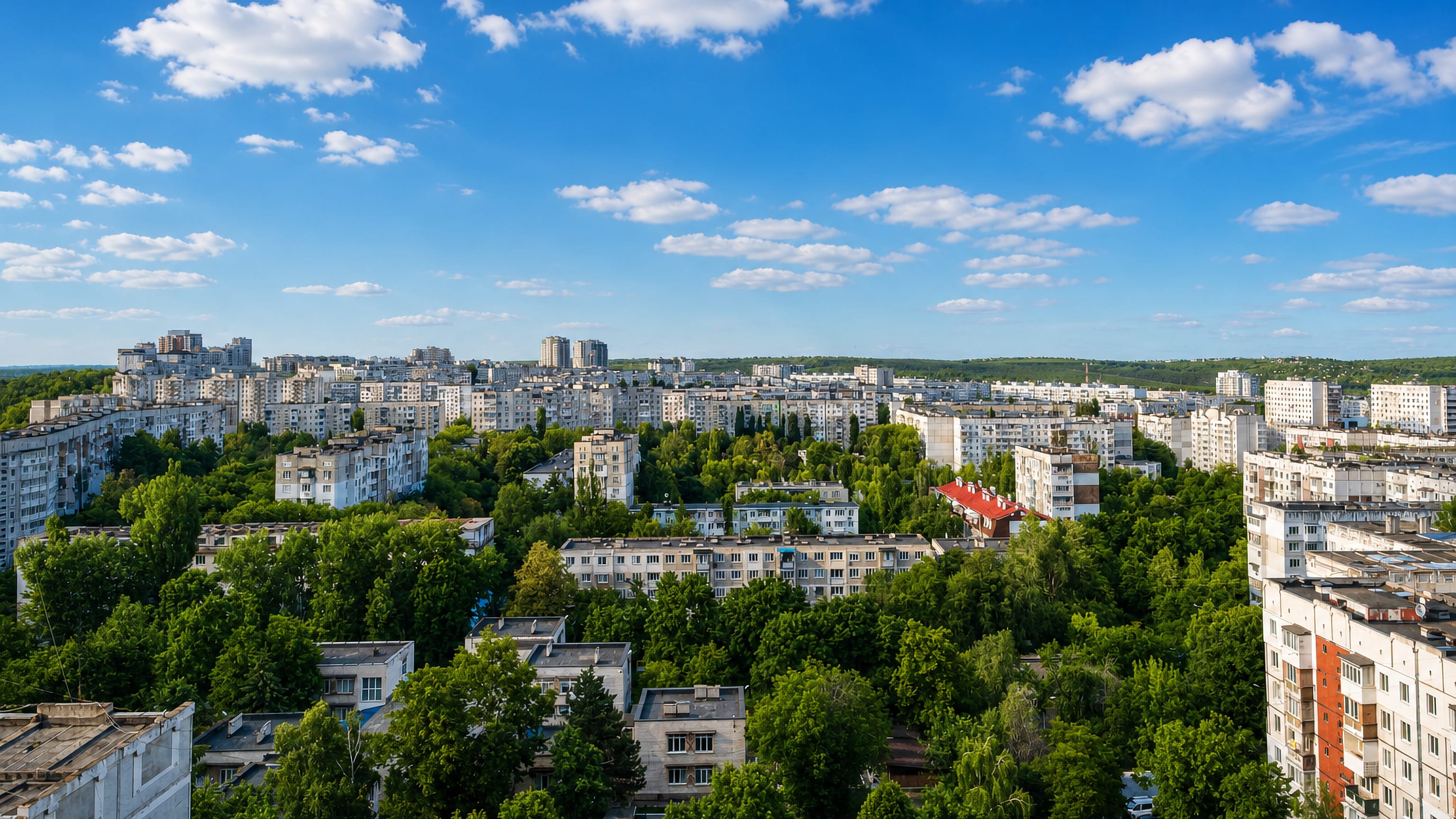 Soviet-era apartment blocks among dense trees under a blue sky in the Ciocana sector of Chisinau.