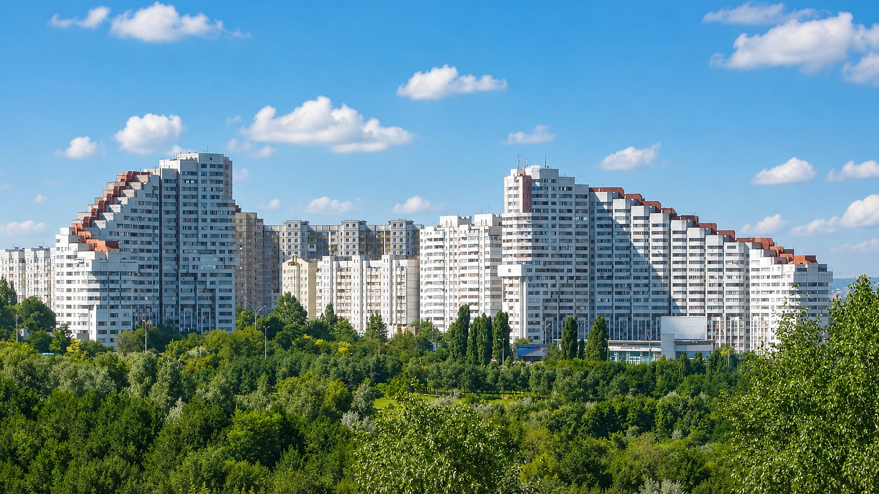 The stepped City Gates towers of Sectorul Botanica in Chișinău rising above a broad belt of parkland