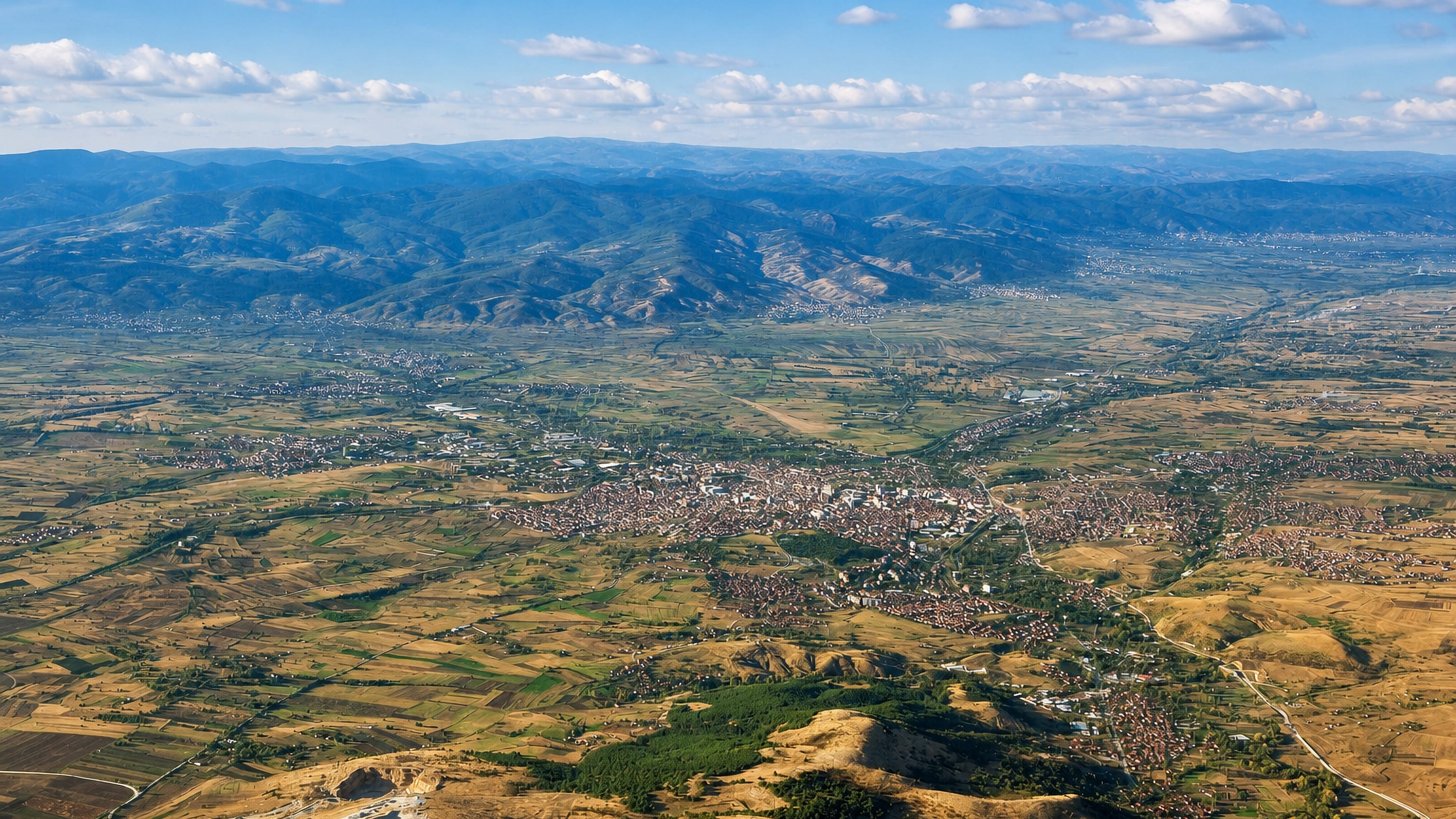Aerial view of Kumanovo spread across its broad farmed valley below the hills of northern North Macedonia.