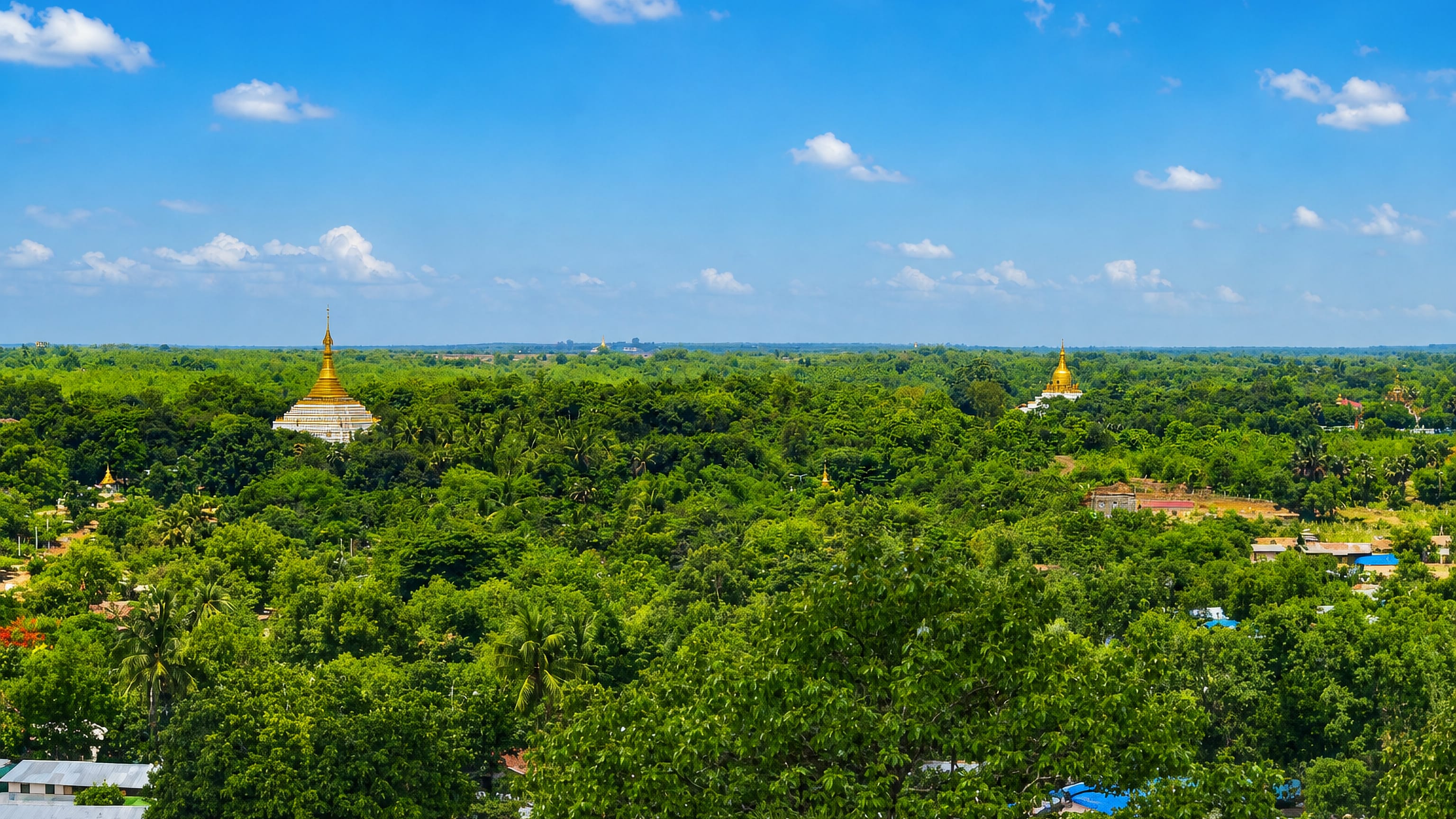 Golden pagoda spires rising above dense tree canopy and rooftops in Bago, Myanmar