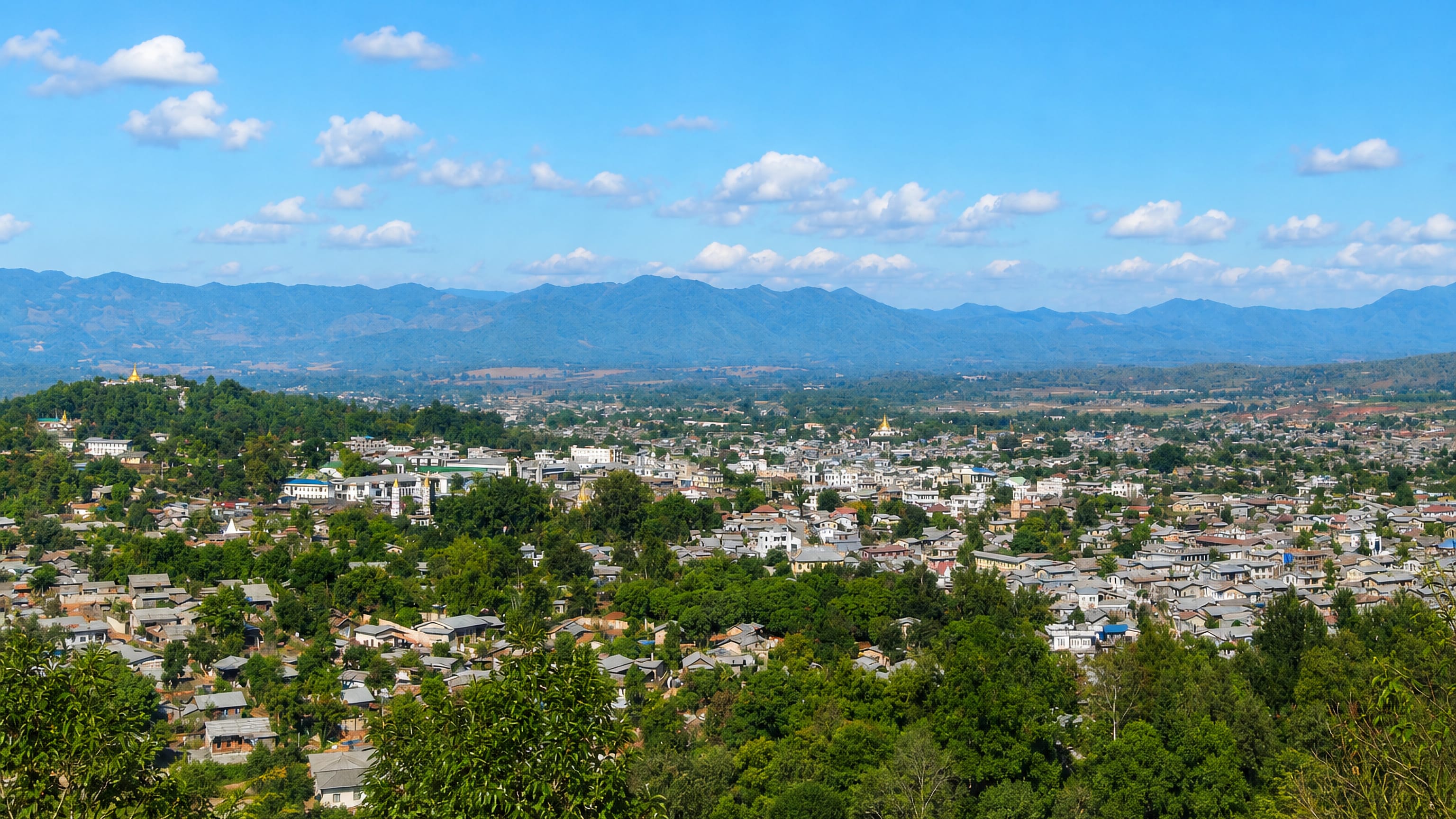 Lashio spread across the Shan hills of Myanmar, with a gilded hilltop pagoda and mountains beyond.