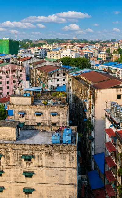 Rooftop view over Yangon's densely packed, colourful weathered mid-rise apartment blocks.