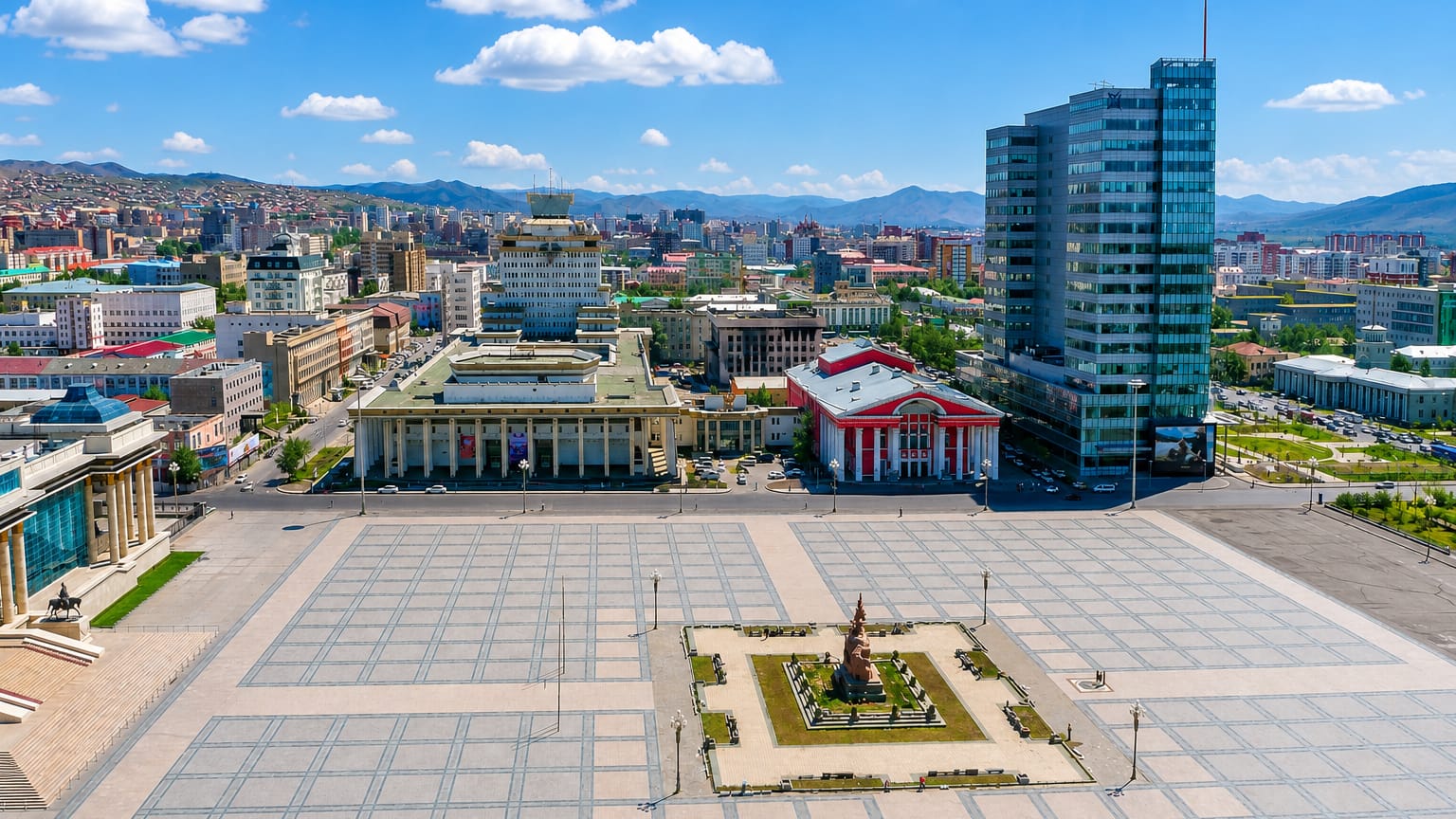 Ulaanbaatar's Sukhbaatar Square with government and theatre buildings, a central monument and mountains behind the city.