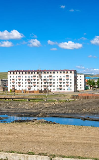 Soviet-era apartment blocks and low houses backed by open steppe hills in the Nalaikh district of Ulaanbaatar.