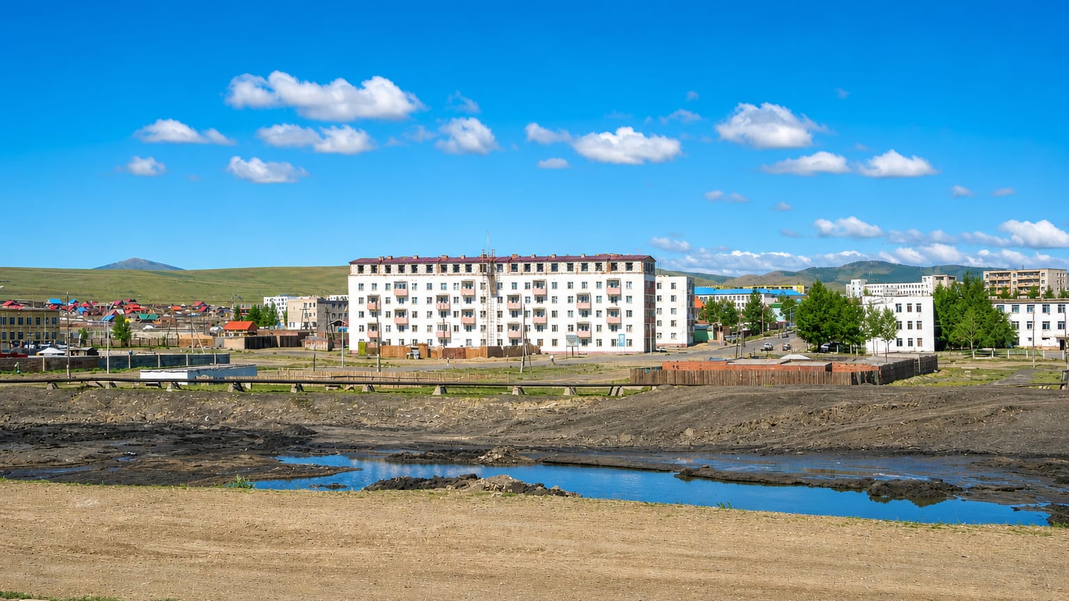 Soviet-era apartment blocks and low houses backed by open steppe hills in the Nalaikh district of Ulaanbaatar.