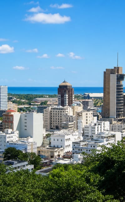 Port Louis skyline of towers and its Indian Ocean harbour seen from the green hills above the Mauritian capital