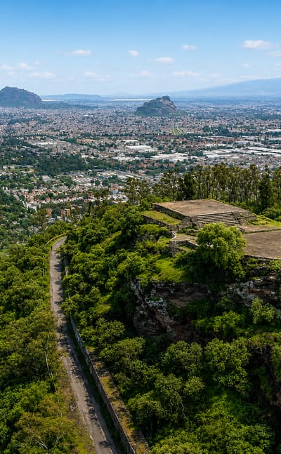 Cablebus cable cars over dense hillside housing and a park in Iztapalapa, Mexico City