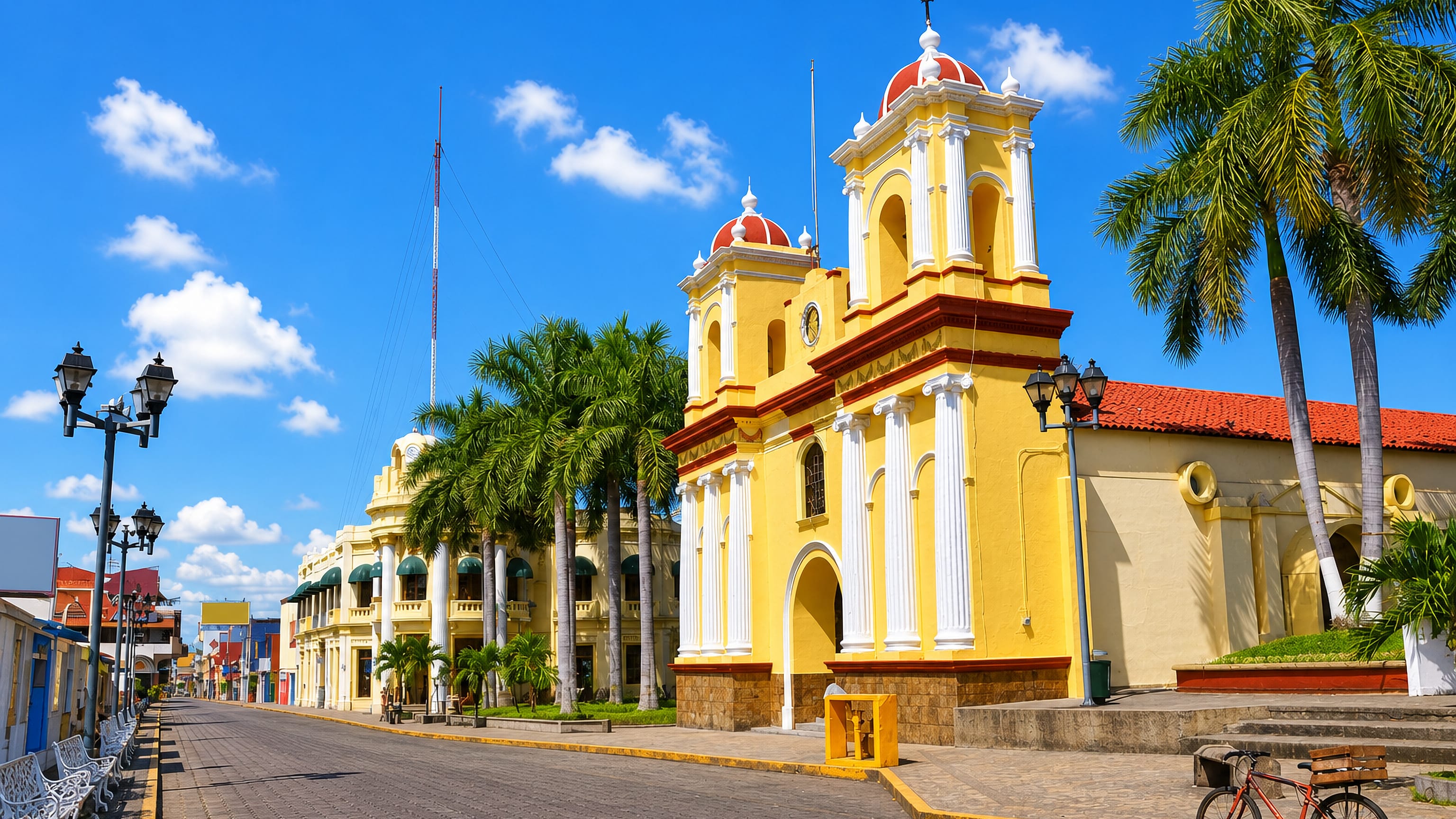 A yellow twin-towered church and colonnaded colonial buildings on a palm-lined street in Tapachula, Chiapas.