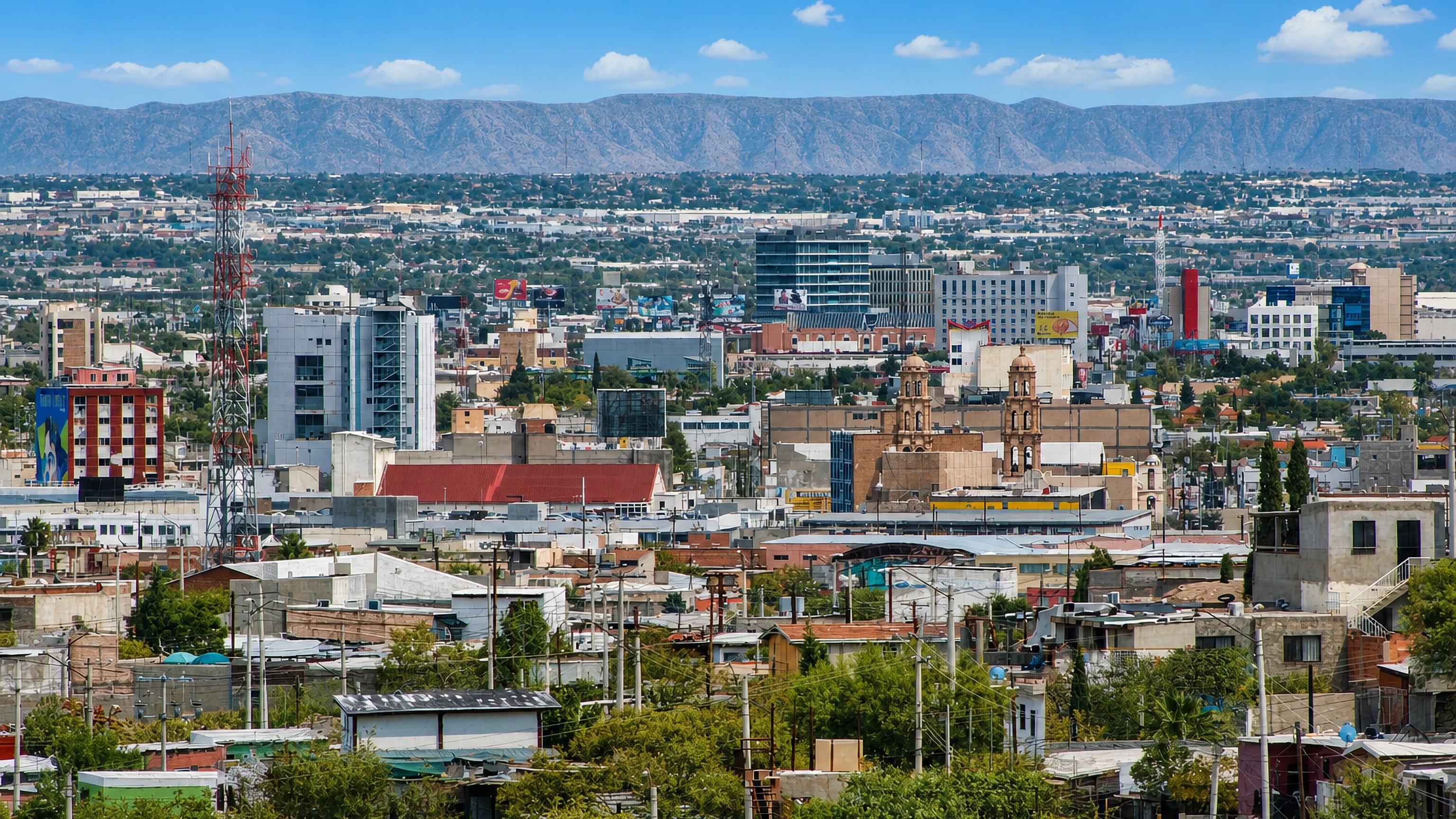 Sprawling Ciudad Juarez rooftops with a twin-towered church and desert mountains on the horizon.