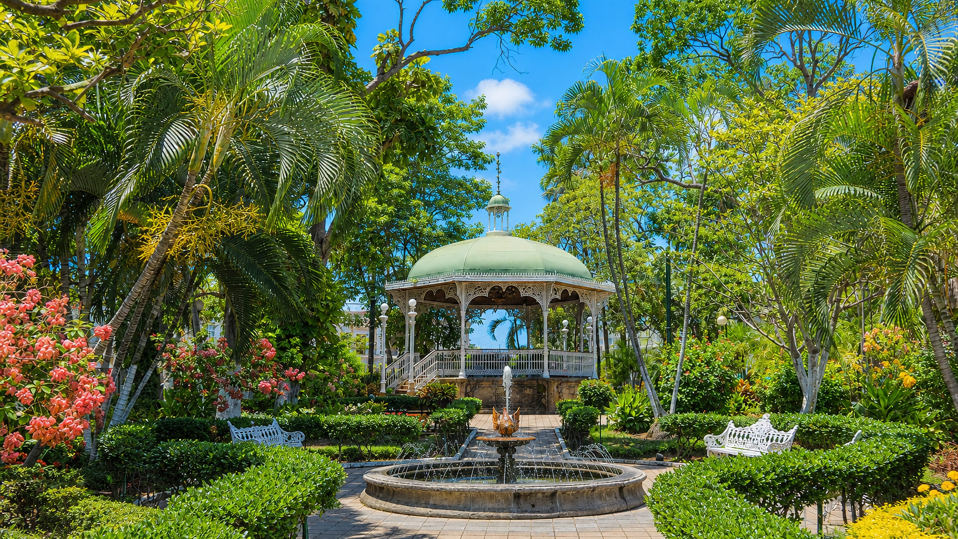 White wrought-iron bandstand and a fountain among palms in the central garden of Colima, Mexico.