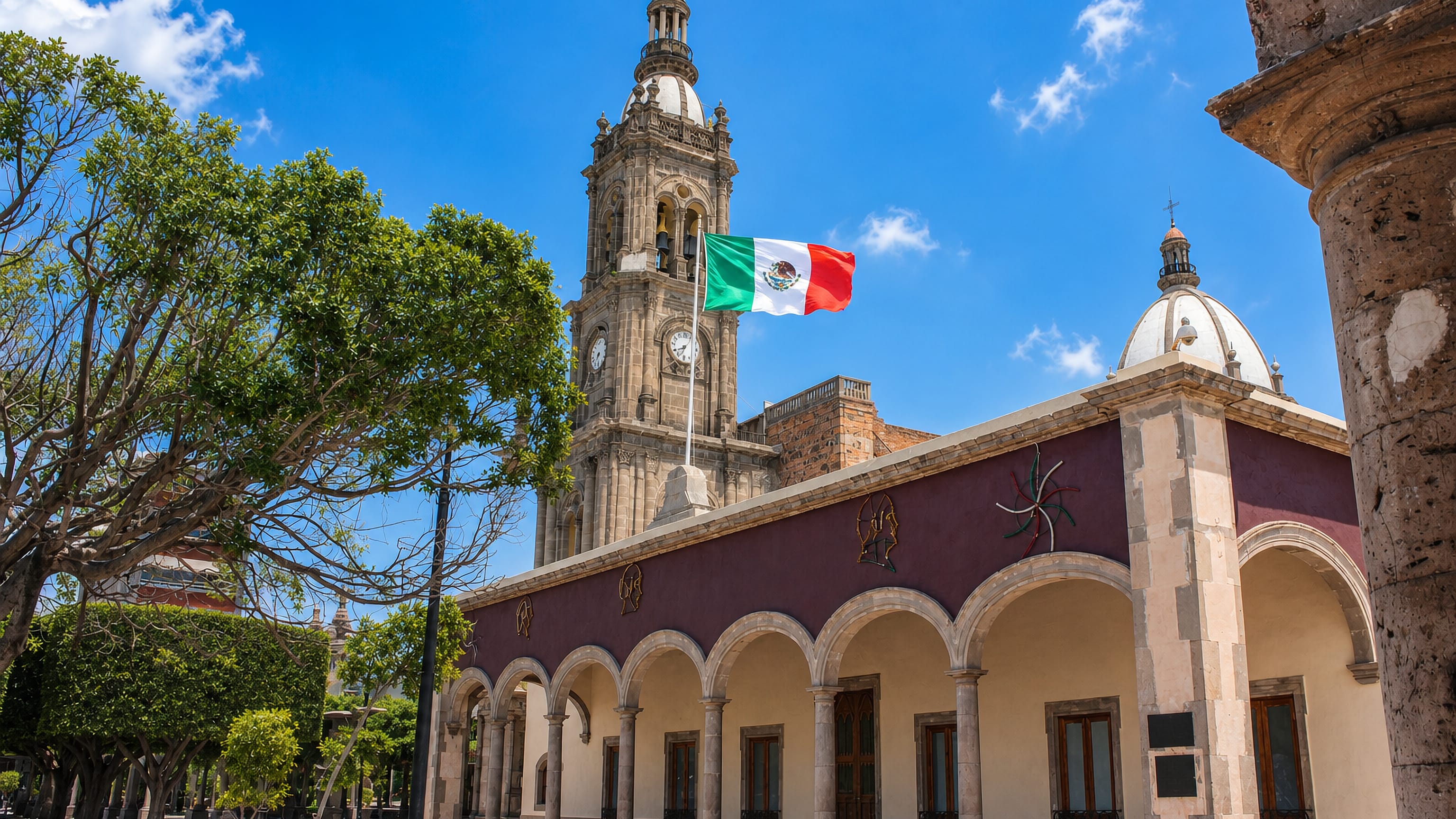 Baroque church tower, Mexican flag and arcaded portales on the main plaza of Salamanca, Guanajuato.
