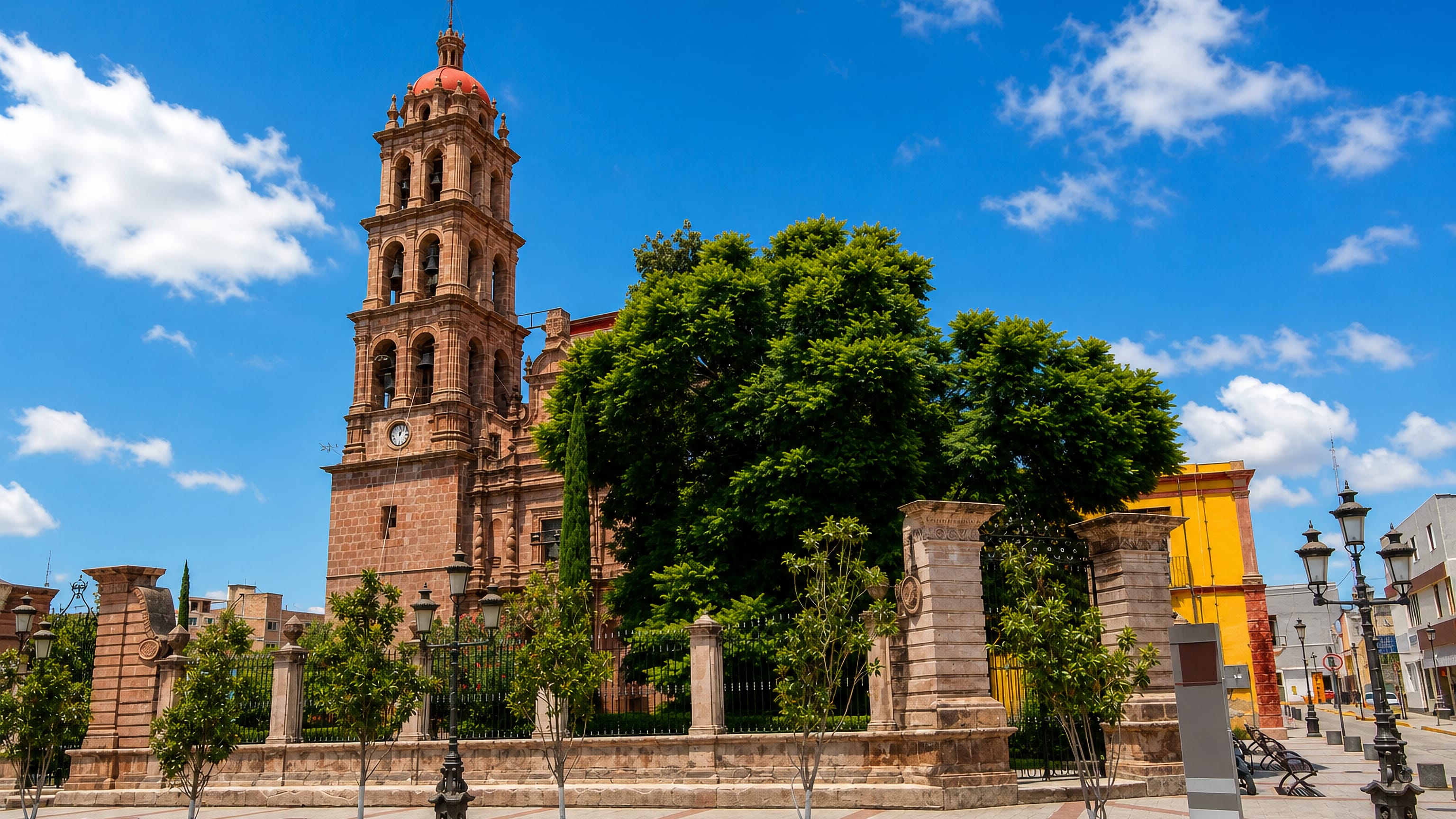 Pink stone parish church with a bell tower and red dome on the central plaza of Silao de la Victoria, Mexico.