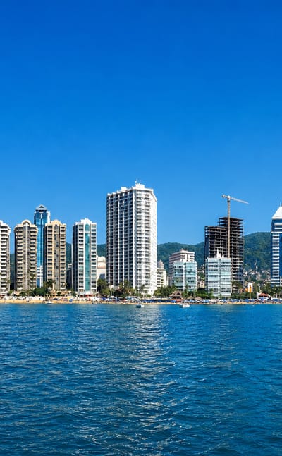 Acapulco Bay hotel high-rises along the beach with hills behind, seen from the water, Mexico