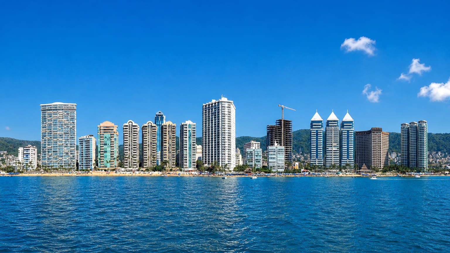 Acapulco Bay hotel high-rises along the beach with hills behind, seen from the water, Mexico