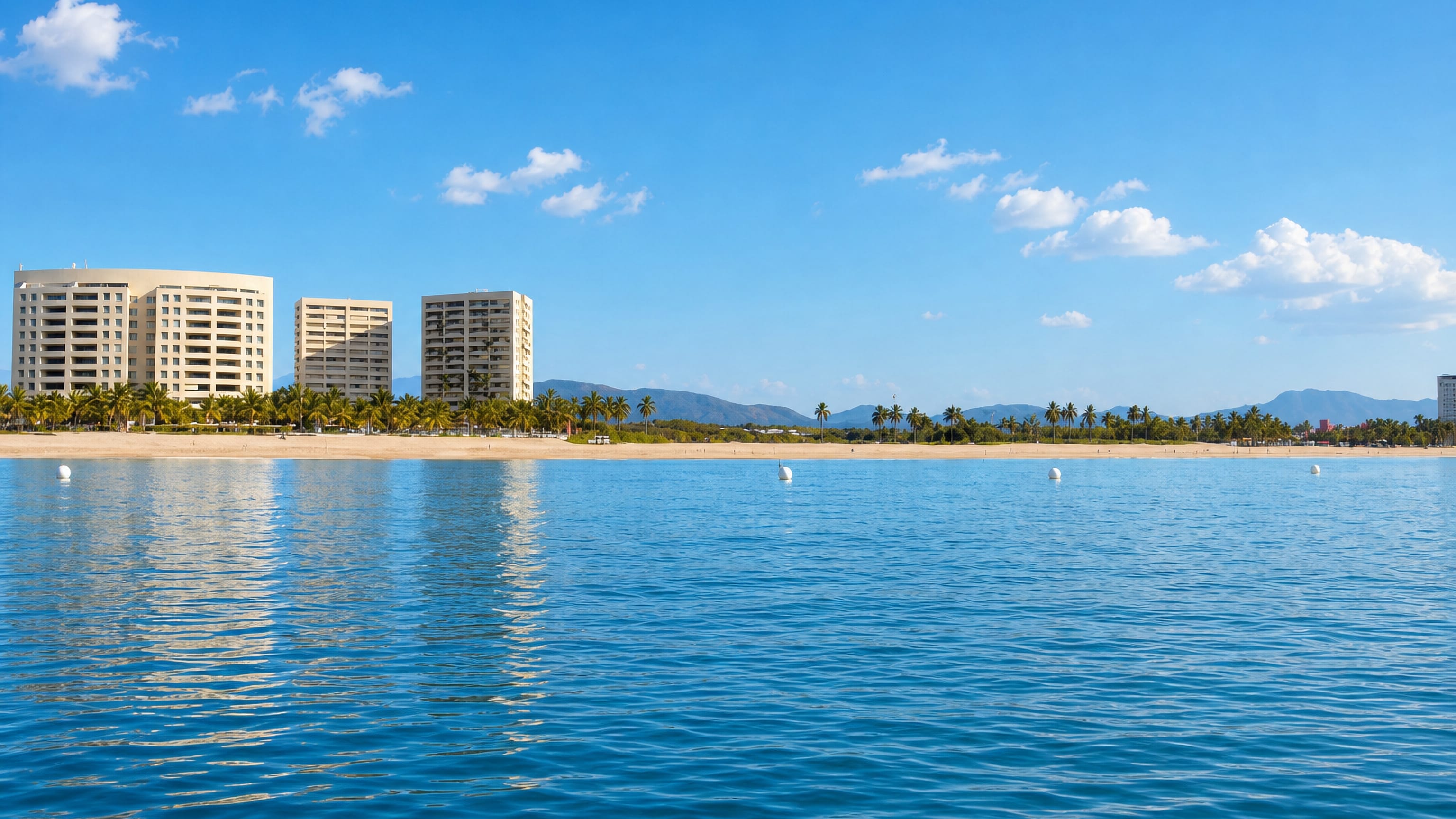 Beachfront hotel towers and palms at Ixtapa-Zihuatanejo, Mexico, seen from the bay with the Sierra Madre behind.